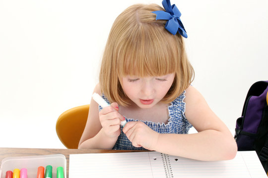 beautiful little girl at desk with box of markers