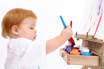 adorable baby girl painting at easel