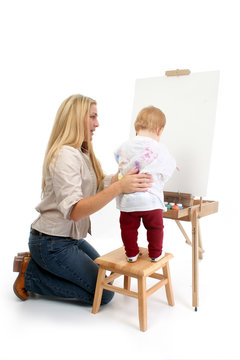 baby girl painting with help from mom