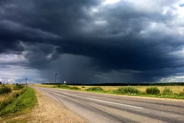 Afwasbaar Fotobehang Onweer regenwolken in de buurt van de landweg.