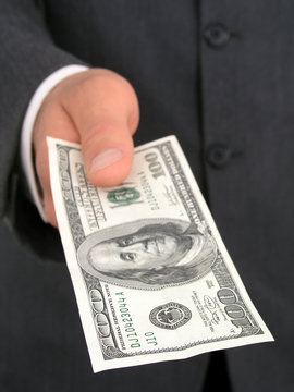 businessman offering one hundred dollar bill