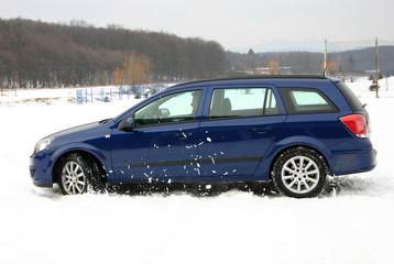 Fototapeta na wymiar Niebieski samochód na śniegu