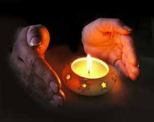 woman's hands lit by a christmas candle