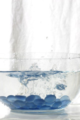 blue glass stones splashing into water