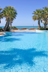 swimming pool in spanish hotel with sea views and palm trees