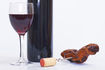 glass and bottle of red wine, corkscrew and white isolated backg