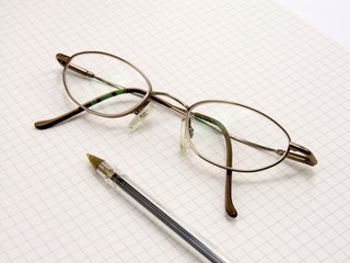 glasses and pen on chequered paper