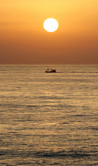 golden sunrise in marbella, southern spain with ocean and boat