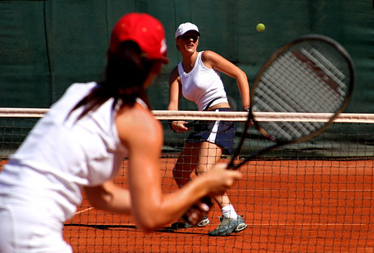 two young sporty female tennis players having a game in the sun.