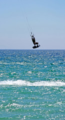 kitesurfer flying high through the air as his kite hits some ser
