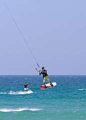 kitesurfer flying through the air on a sunny beach