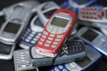 red cellular phone on heap of others. © DaiPhoto
