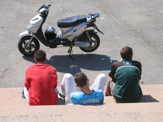 désœuvrement : trois jeunes adolescents désœuvrés et vus de dos assis sur des marches devant un scooter - obrazy, fototapety, plakaty