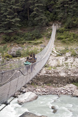 porters crossing a suspension bridge - nepal