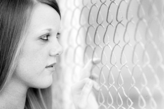 Girl Looking Through Fence