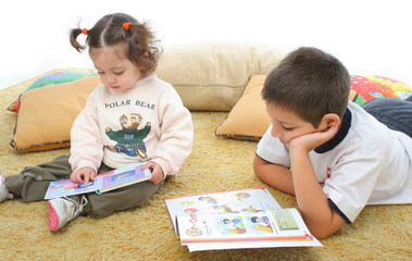 brother and sister reading books on the floor