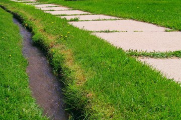 sidewalk and ditch in grass