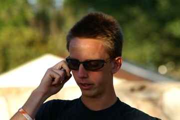 Naklejka na ściany i meble teen boy on cellphone with sunglasses