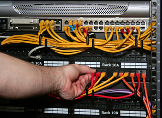 technician plugs a network cable into a patch pane