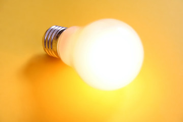 illuminated lightbulb on yellow background