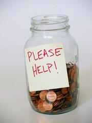 jar full of pennies with "please help" sign
