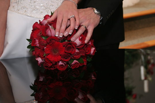 bride & groom ring on hand over flower bouquet