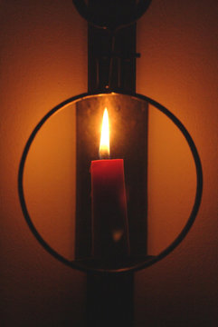 red candle burns behind magnifying glass