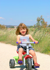 Fototapeta na wymiar enfant riant sur son tricycle
