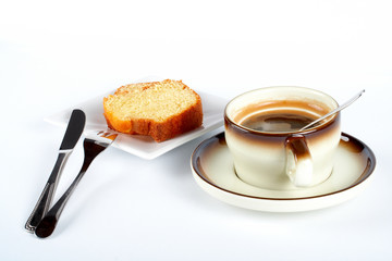 sponge cake with the cup of coffee, spoon, knife a