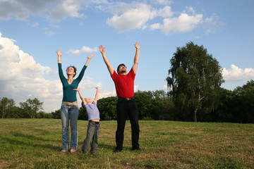 family with hands up on meadow