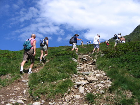 les randonneurs : une file de marcheurs montent une pente couverte d'herbe et de rocaille