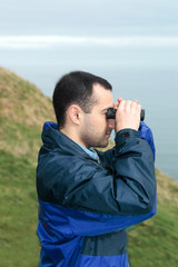 man with binoculars looking at the sea