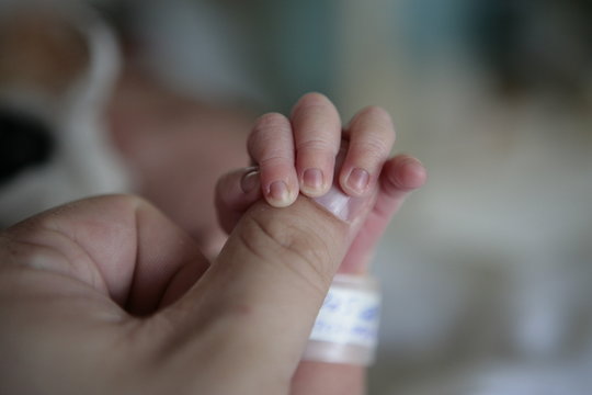 newborn hand on parent's thumb