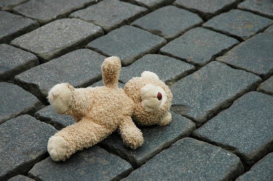 Naklejki little teddy-bear laying on the cobblestones