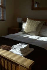freshly made bed with sliver of slatted blind