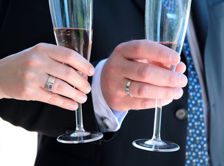 newly weds hands with wedding rings and champagne