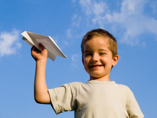 a smiling boy with a paper aeroplane toy