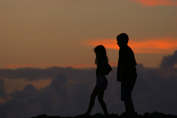 silhouettes of people walking in front of sunset
