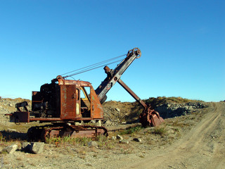 old rusty broken excavator in a quarry near the road