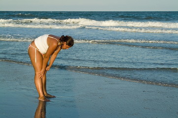 young girl on beach looking for shells