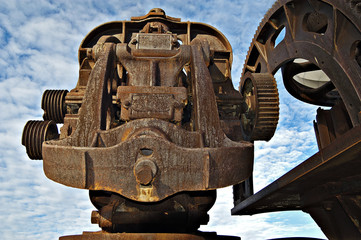 rusted industrial geared machine with sky