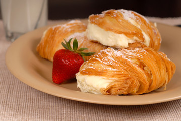 three sfogliatelle's with strawberry on tan plate