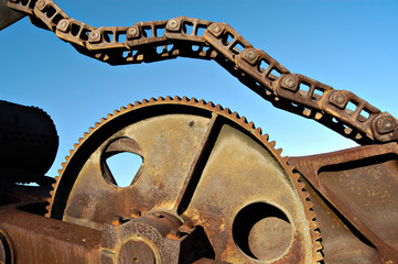rusted industrial gear and chain with blue sky