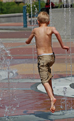 boy running and jumping through a fountain