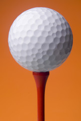 golf ball on red tee, orange background