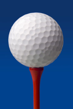 golf ball on red tee, blue background
