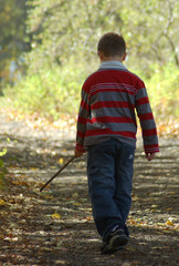 young boy walking with stick
