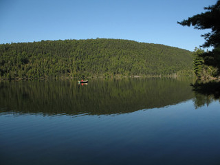 solitary row boat on mirror-like lake