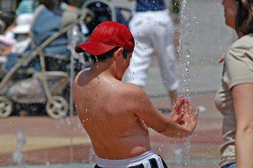 boy playing in fountain getting sprayed by water