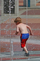 young boy running and playing in fountain